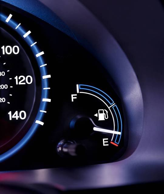 A car interior, the dashboard,instrument panel,and fuel gauge. A speedometer