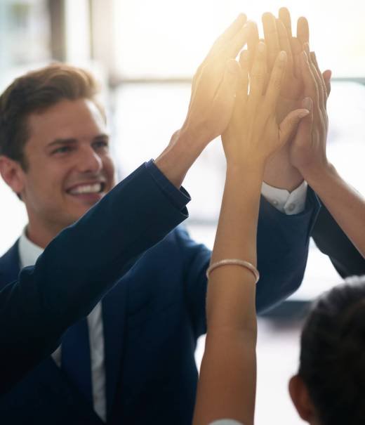 Cropped shot of a group of businesspeople high fiving together in an office.